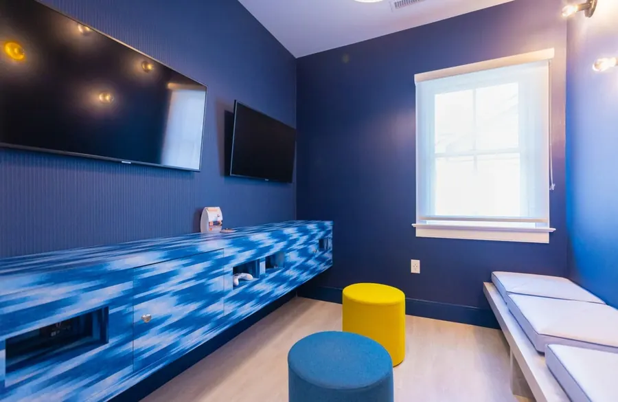 The game room at Summit Dental Partners, with televisions, benches and bright stools.